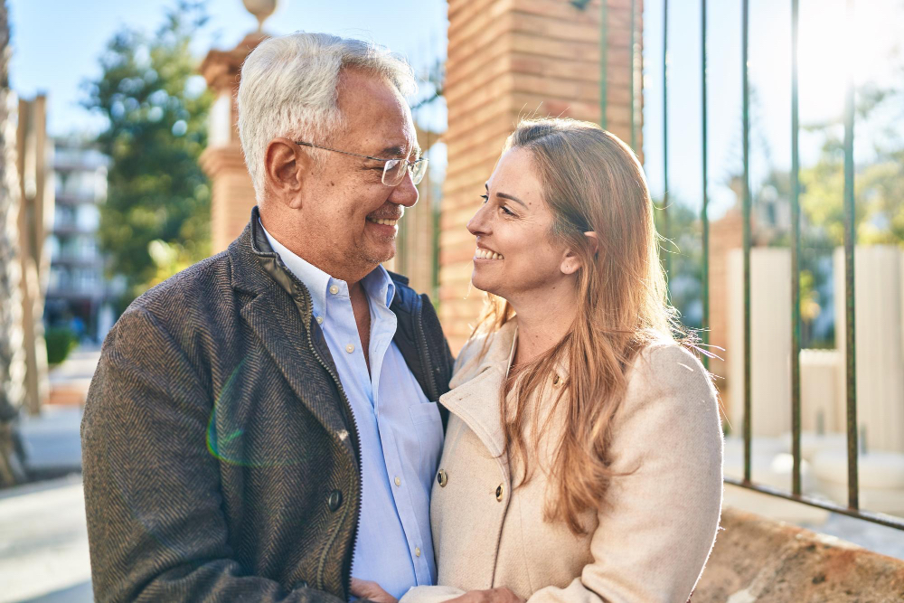 Una coppia si guarda negli occhi sorridendo in una via assolata