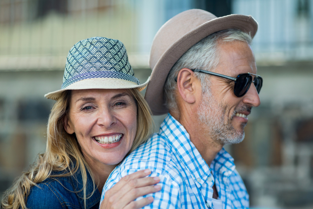Una donna e un uomo sorridenti con cappelli estivi in città